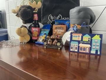 花生旁边放着一张“欢迎回家”的贺卡, 根啤酒, 一只毛绒驼鹿和其他的好东西放在一个爱心包裹里.